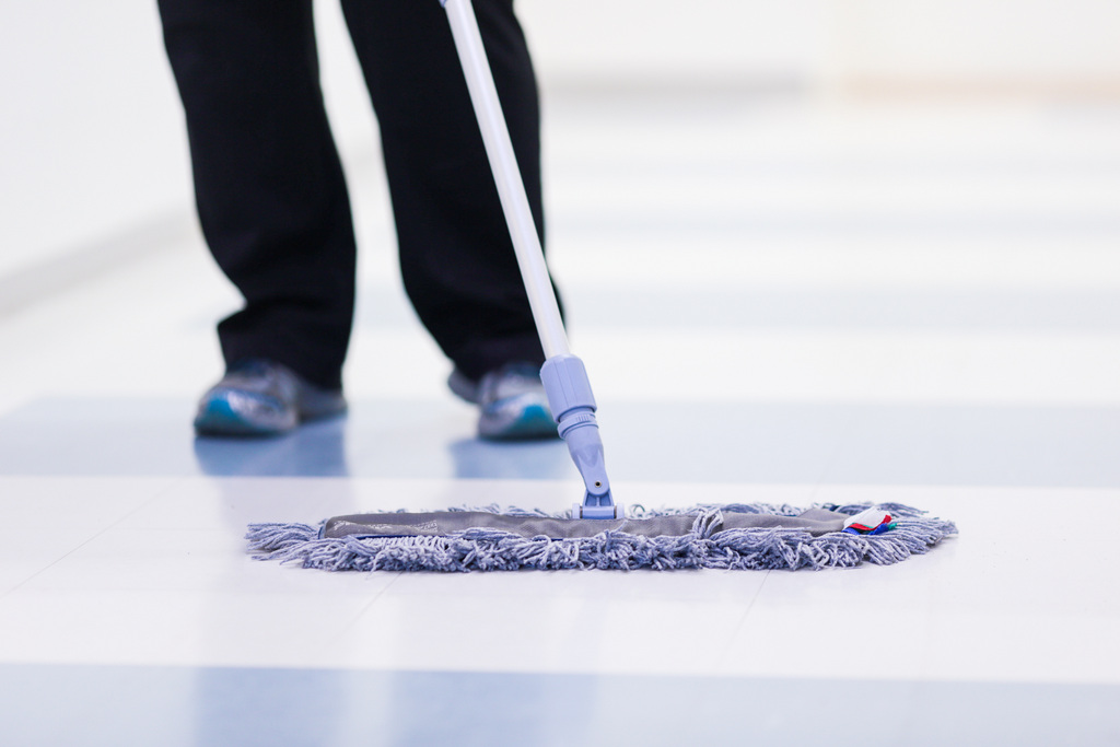 Siivooja pyyhkii vaaleaa lattiaa leveällä mopilla. Ravimäki Haminassa tarjoaa rivitaloasukkailleen asiointipalvelua, siivouspalvelua ja talonmiespalvelua.